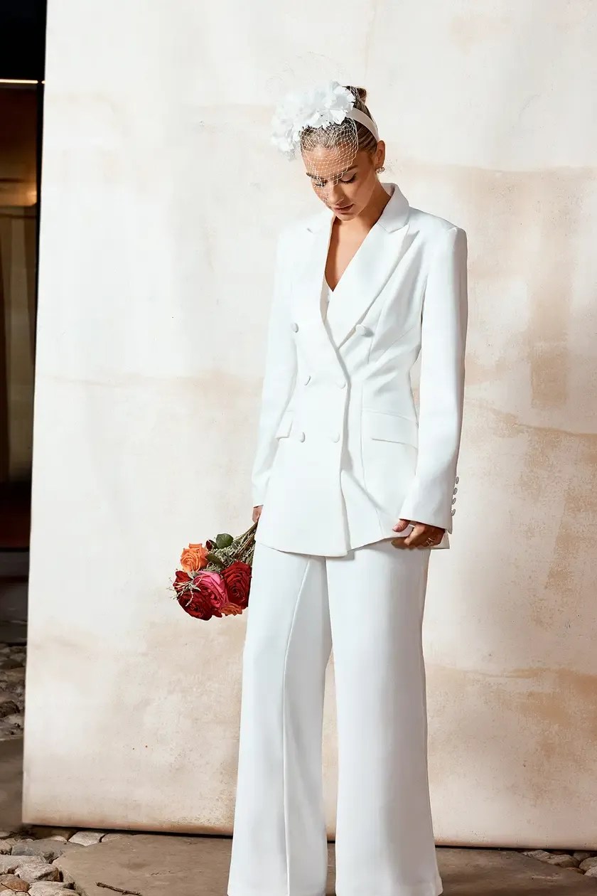 Modern bride in an ivory tailored civil ceremony outfit with white heels and handbag